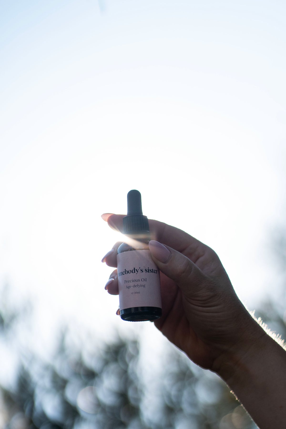 Somebody's Sister Precious Oil bottle held up in sunlight